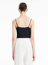 A woman wears a black camisole top and black pants.